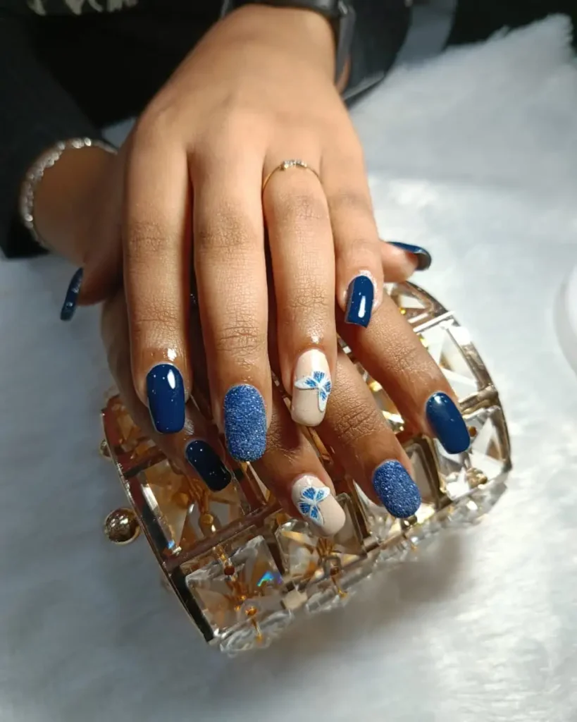 Blue glitter nail art design with floral nail extensions in Thrissur