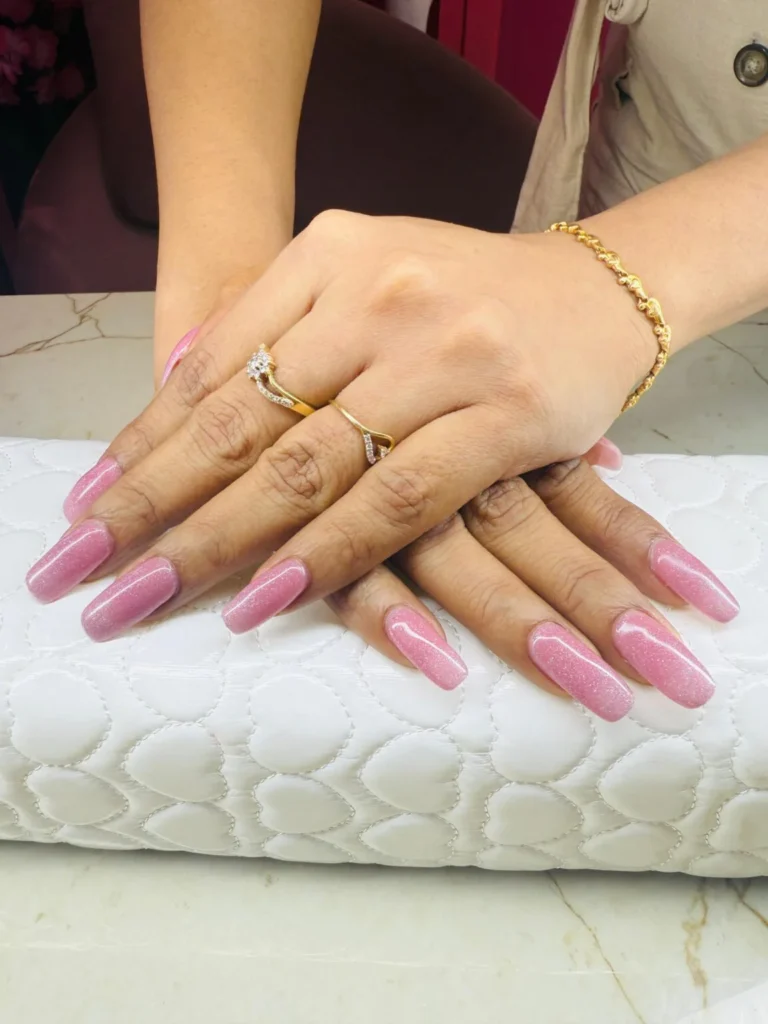 Glossy pink shimmer acrylic nails in Thrissur